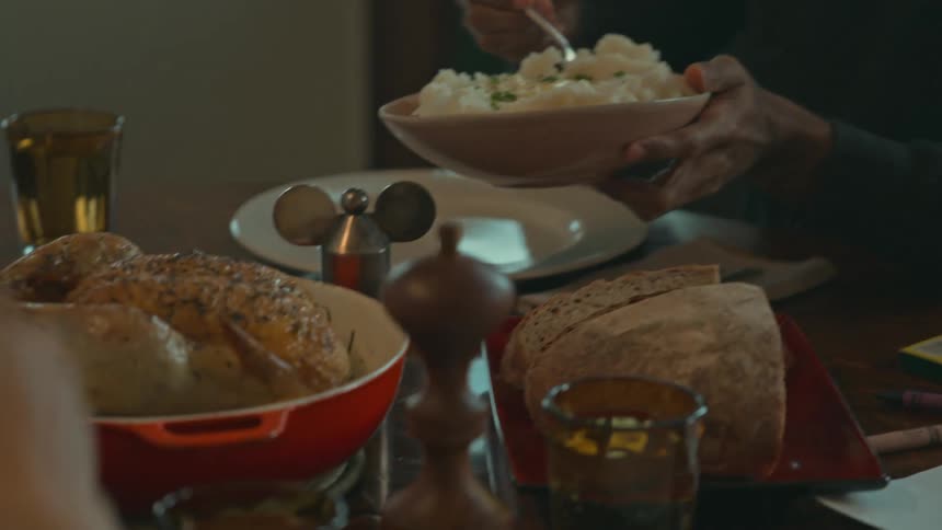 People are at a table dishing up food onto their plates