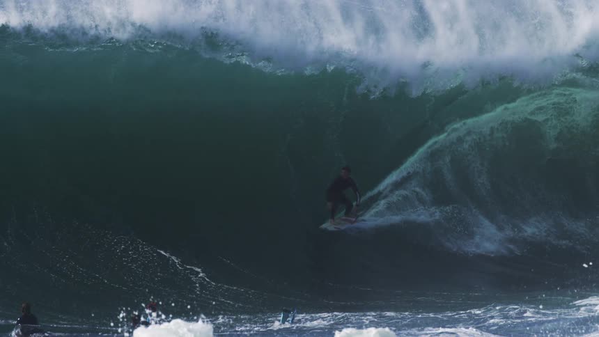 Surfer surfs a large crashing wave in daytime
