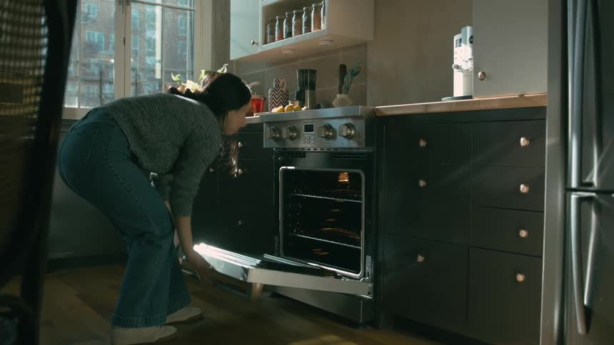 A woman places food in her oven