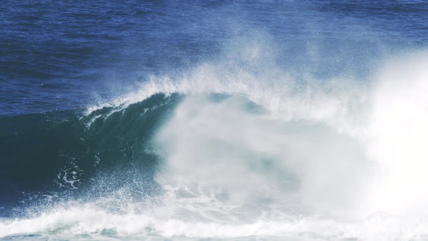The large wave crashes in the ocean