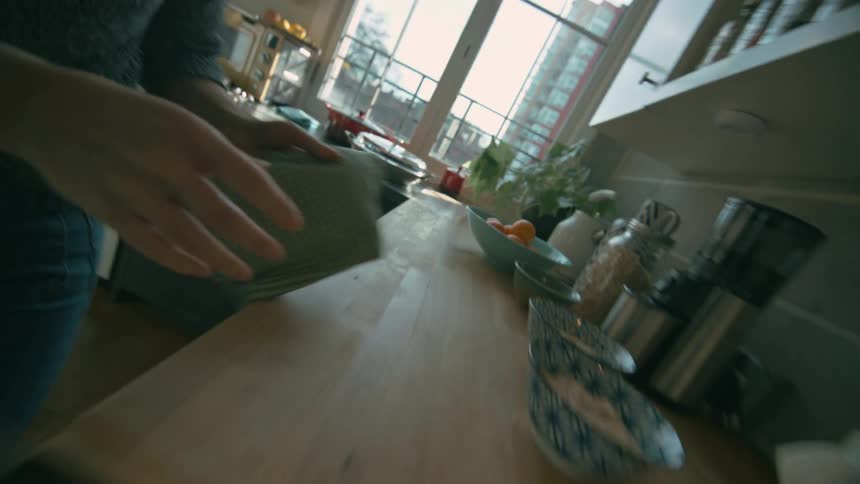 A woman wiping spilled milk off the stovetop using a cloth