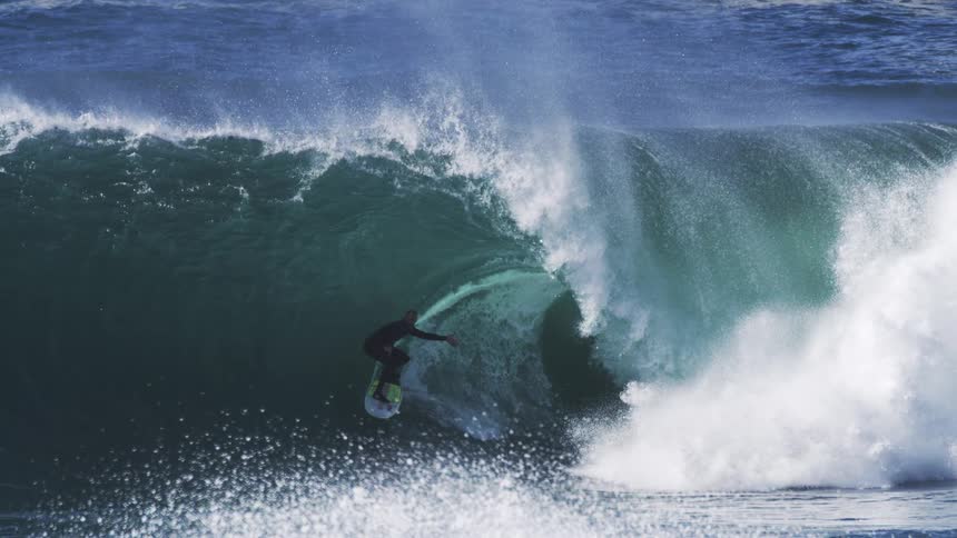 A surfer riding the barrel of a huge ocean wave