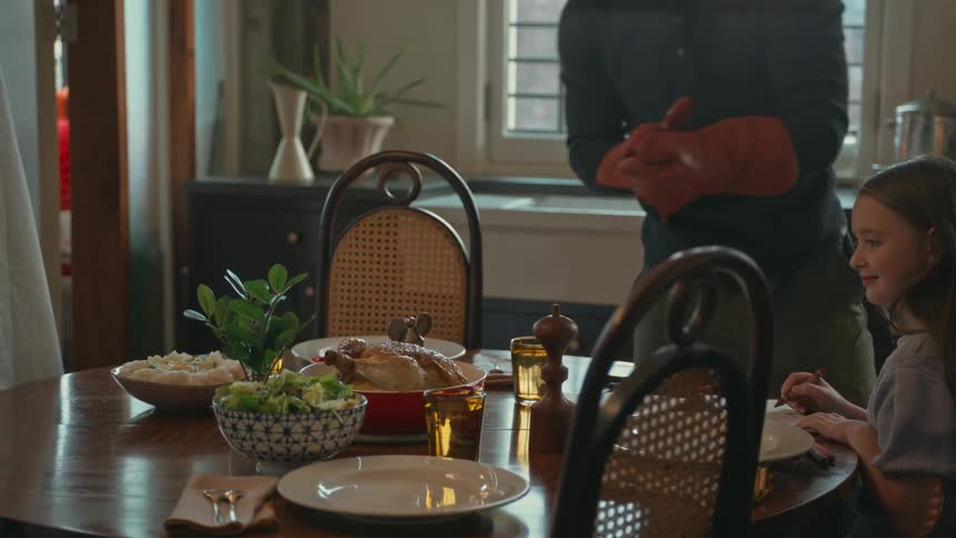 A family of three are getting ready to have a roast chicken dinner in their dining room
