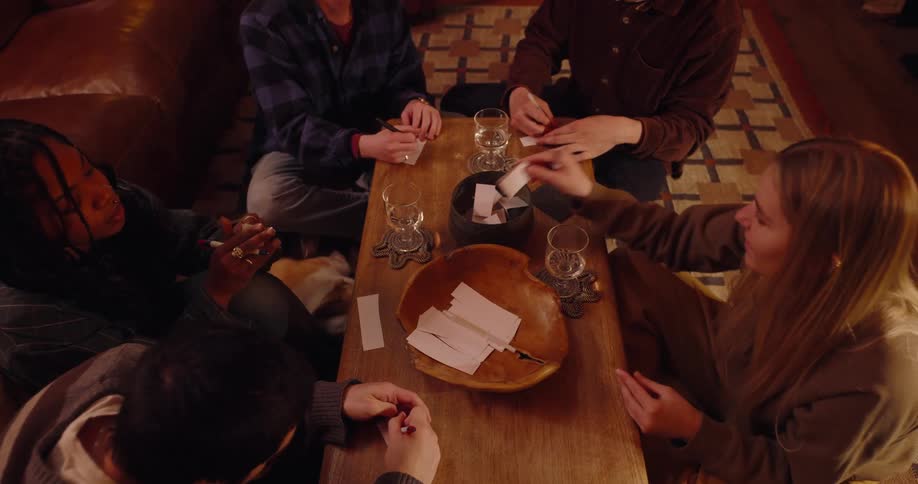 Group of friends sitting around a table writing on a white paper