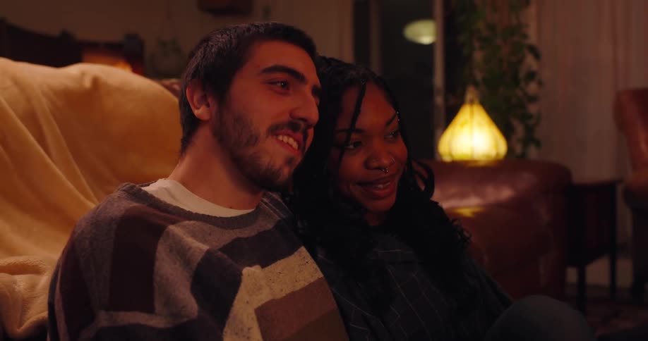 Friends sitting in a living room at night talking and taking pictures