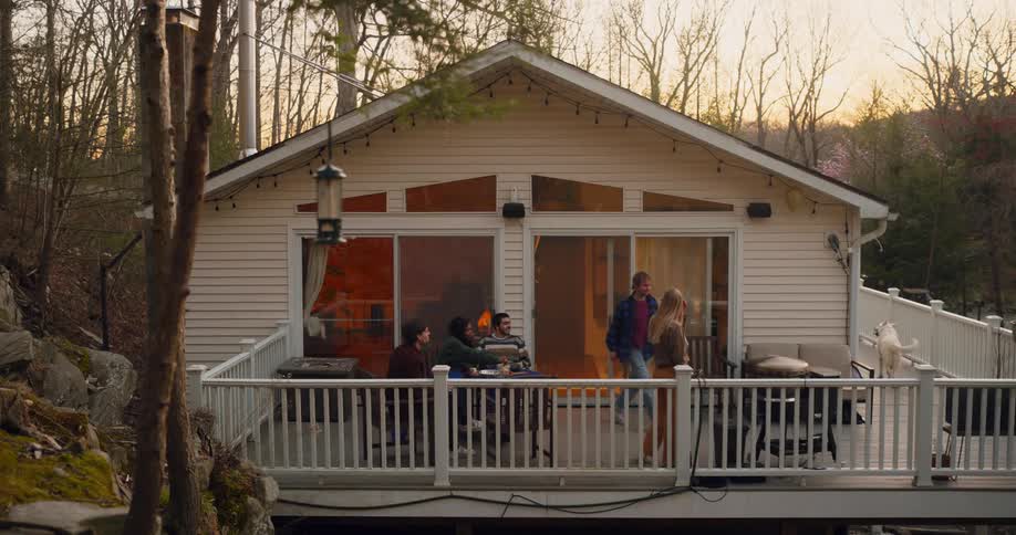 Friends and a dog gathered on large deck on a house in the wilderness for a bbq