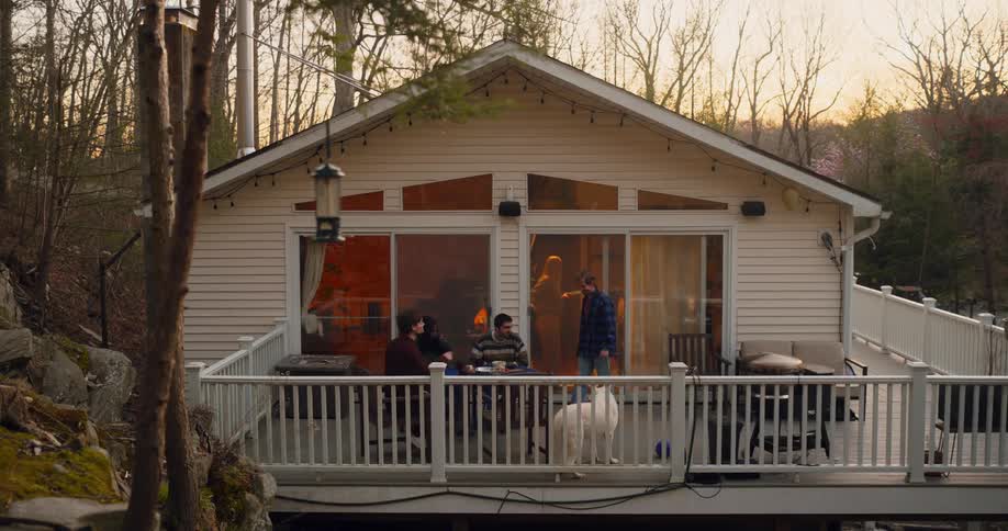 Friends and dog gathered on large deck on a house in the wilderness for a bbq