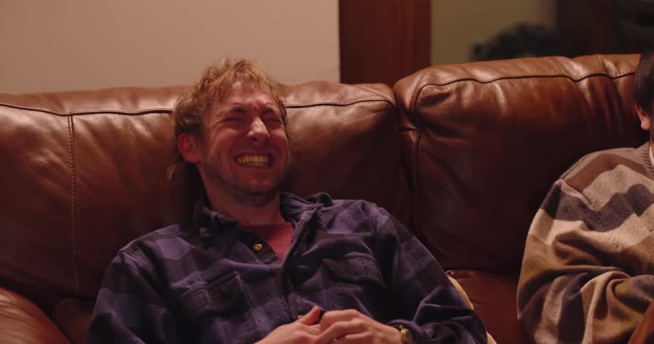 Three friends sitting on a couch laughing