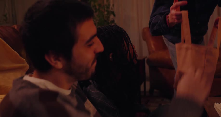 Friends sitting in a living room at night talking happily