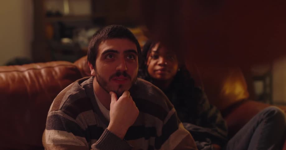 People sitting on a couch watching a person standing and moving their hands