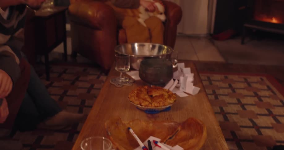 Four friends gathered in a living room one of them holding a pie and placing it on the table