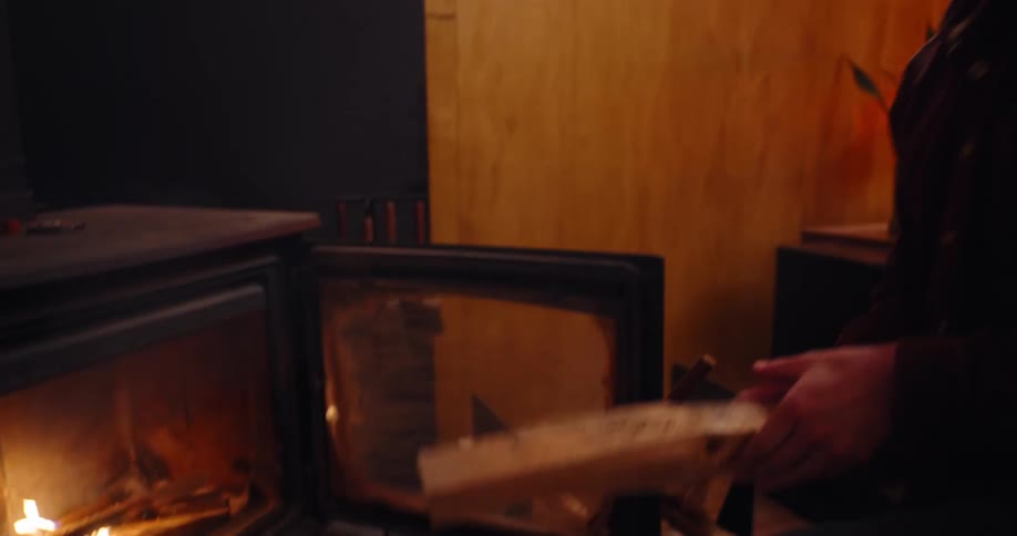 A man places wood in the wood stove
