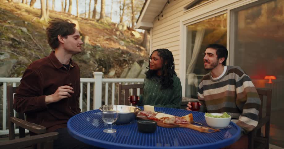 Friends sitting on a porch around a table and toasting