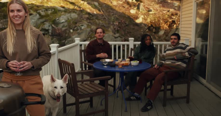 Group of friends having fun and chatting during a barbecue and a dog following along