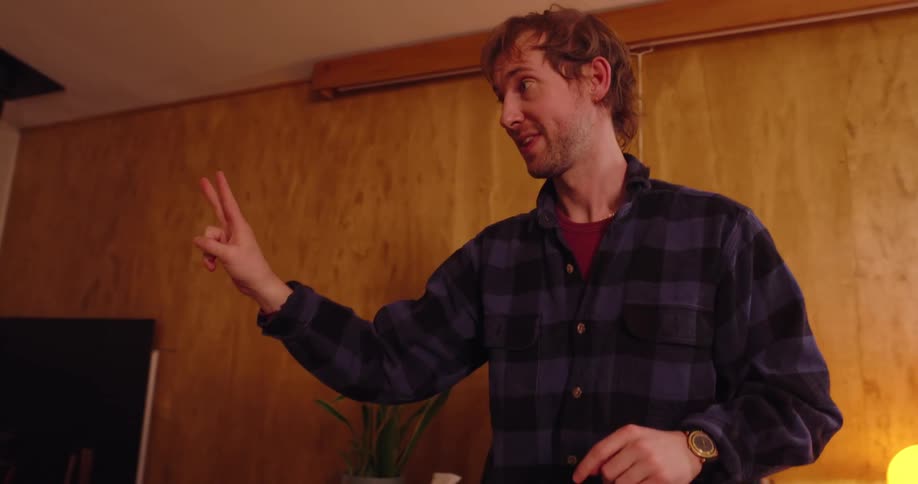 Man holding out two fingers pointing and acting out his words playing charades