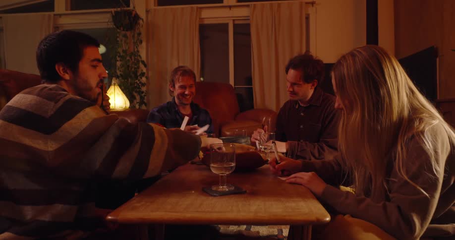 Friends sitting on the floor around a table and writing on white papers