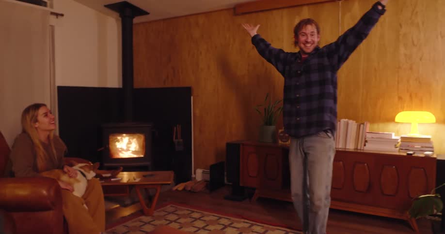 Man demonstrates a word in front of a group of friends as they play charades in a living room