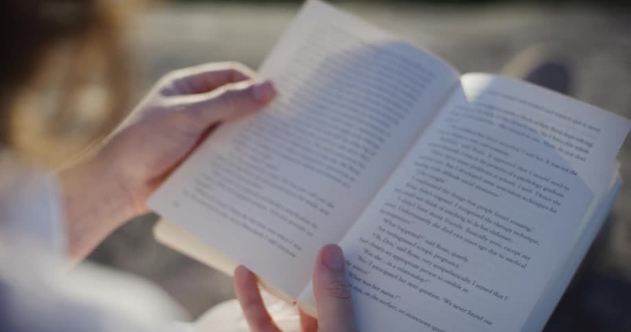 Pair of hands leafing through a book outdoors