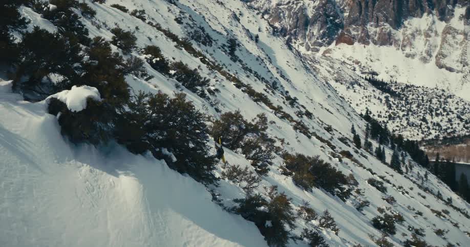 Aerial view of a snowy mountain with a lake in the background