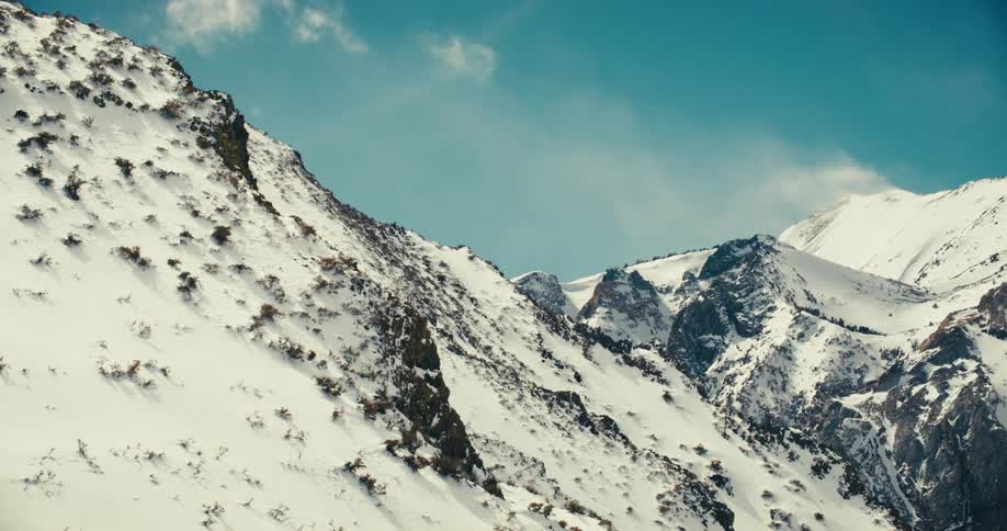 A mountain completely blanketed in snow under a clear blue sky on a sunny day