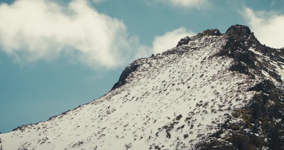 Clouds move over a snow covered mountain peak
