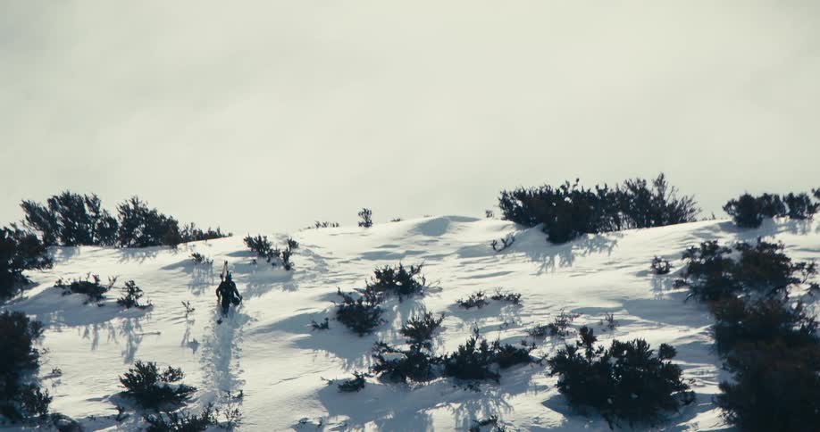 A man is slowly climbing up a snow covered mountain
