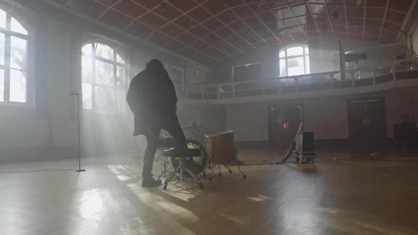 Man sitting in front of a musical drum set in a lobby