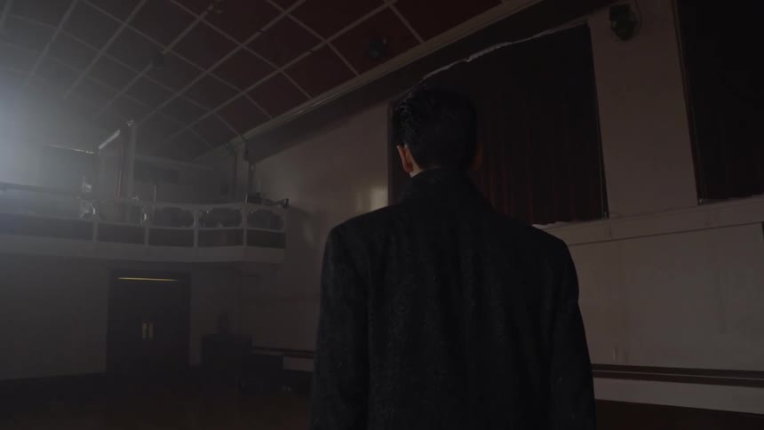 Man walking into a hall and starting to play a guitar
