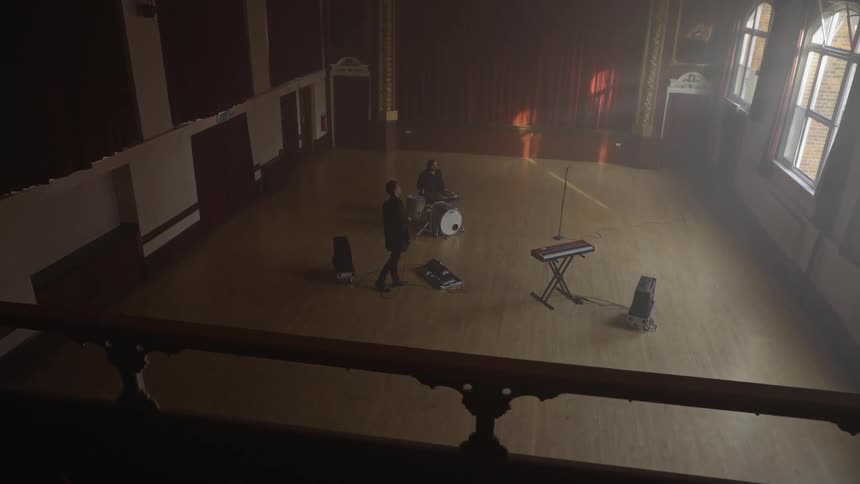 Three musicians playing guitar drums and keyboard are rehearsing before their performance