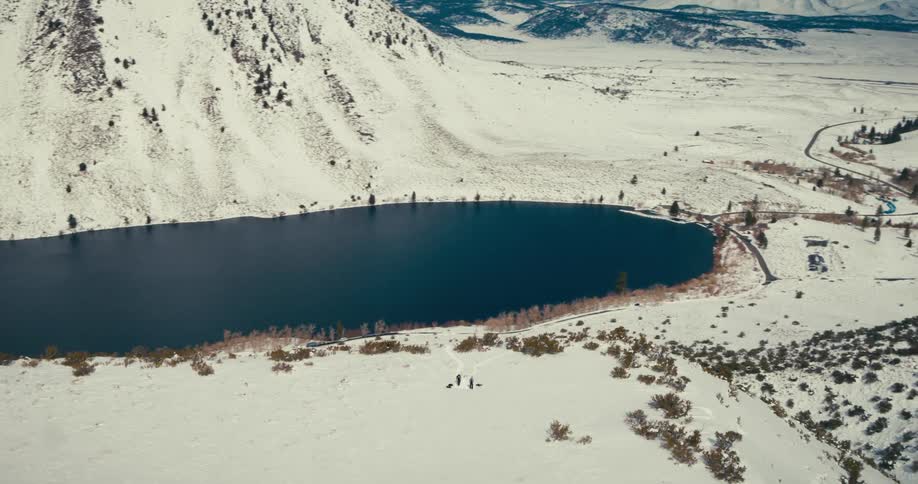 Aerial shot of a lake surrounded by snowy mountains