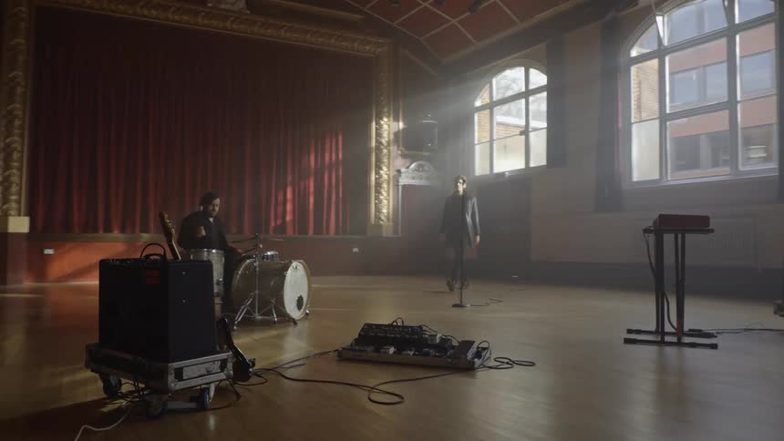 Man playing drums and another person coming in and picking up a guitar