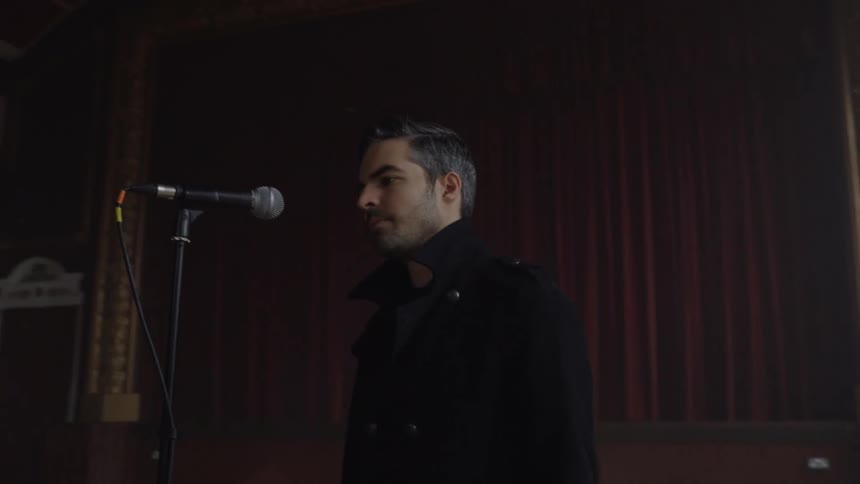 Man walking into a hall and starting to sing into a microphone