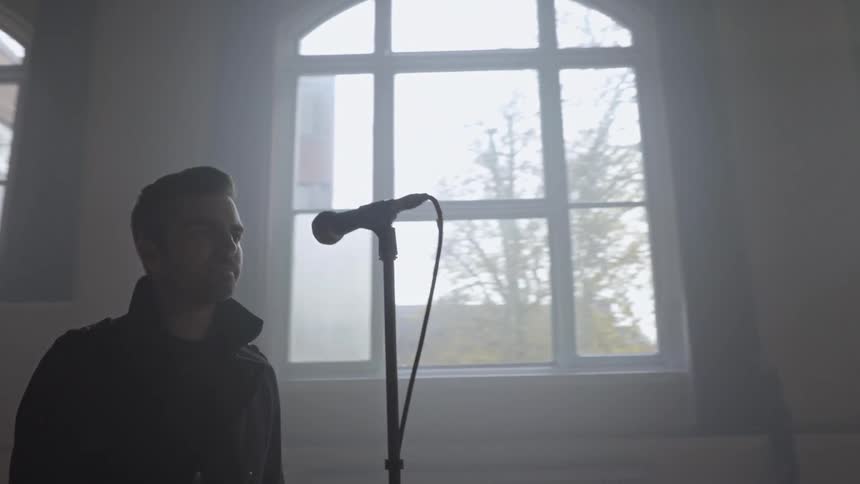 Man singing into microphone along with his band