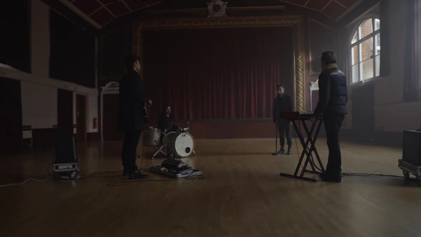 Musicians stand in a circle at their instruments