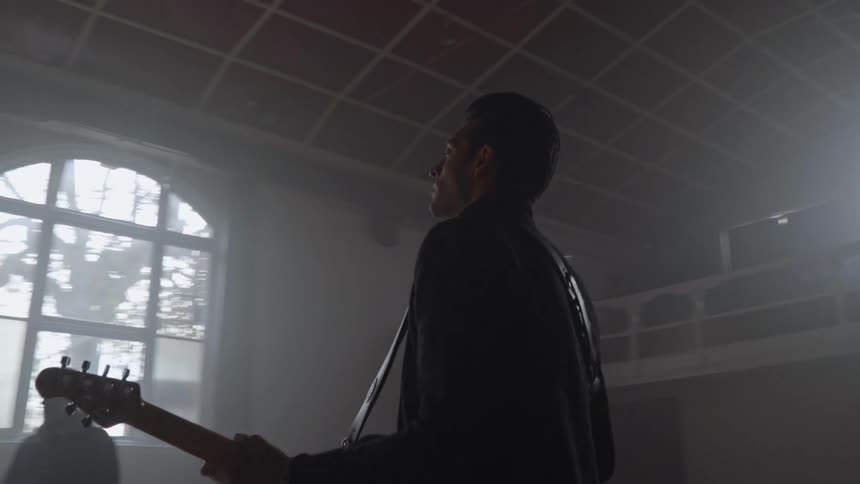 A guitarist plays and rehearses with a band in a large room
