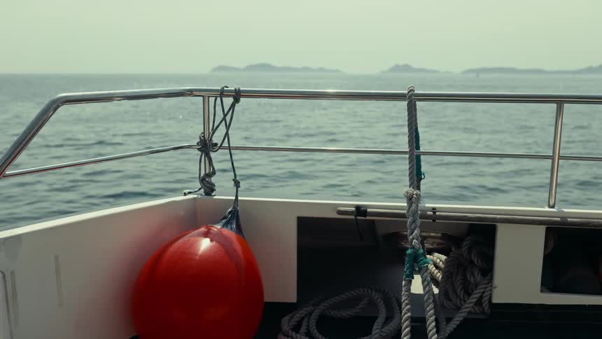 Boat moving across the ocean with the coast on the horizon