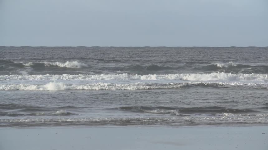 Waves crash on a beach on a clear day