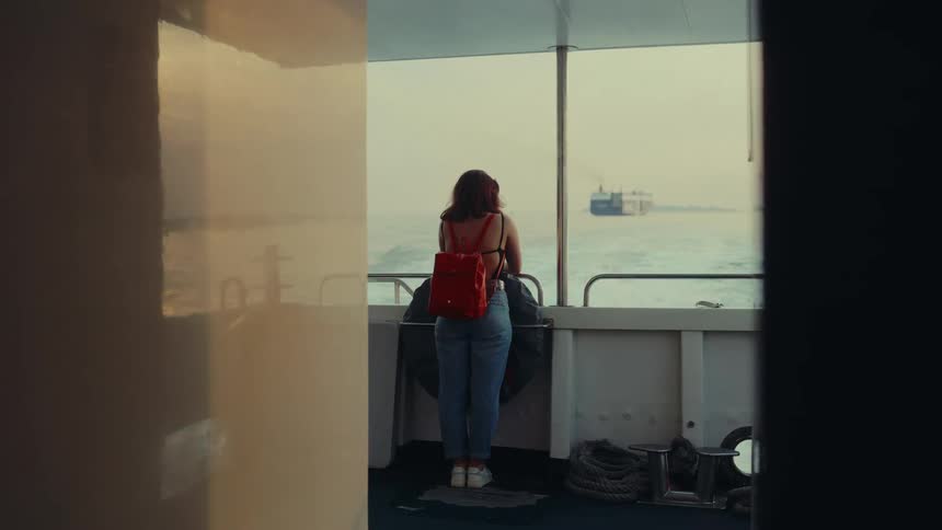Woman stares into the ocean on a ship deck