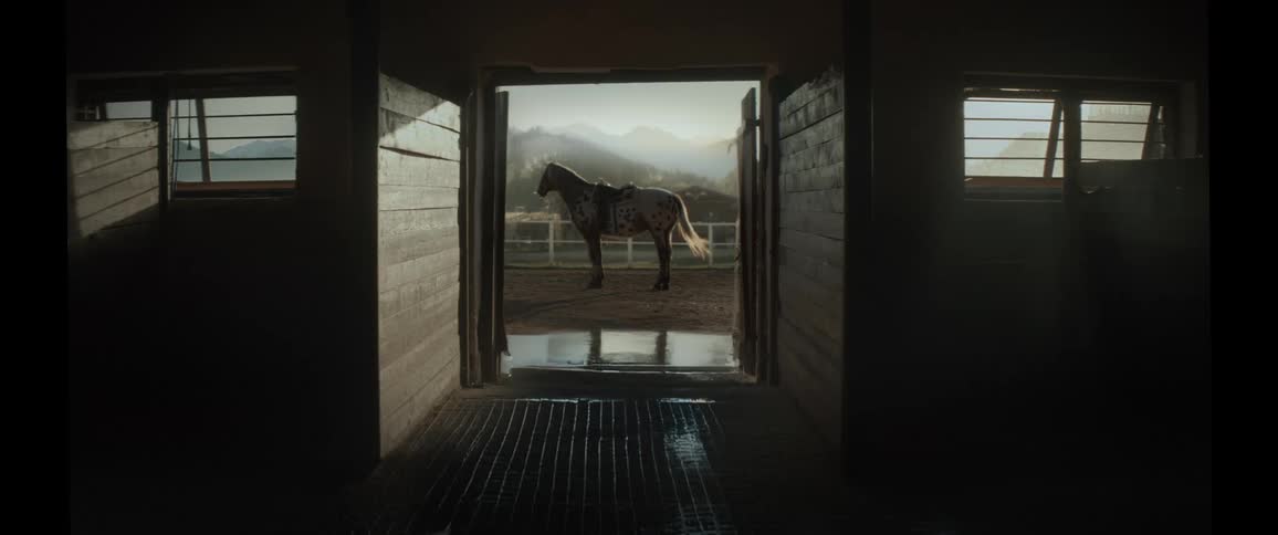 A horse outside a stable with large mountains in the horizon