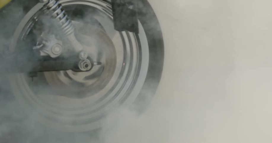 A motorcycle blows out smoke as a person rolls it along the ground