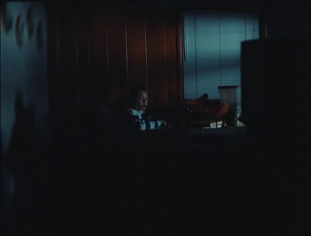 Little blonde girl alone in a room with a play of lights and shadows