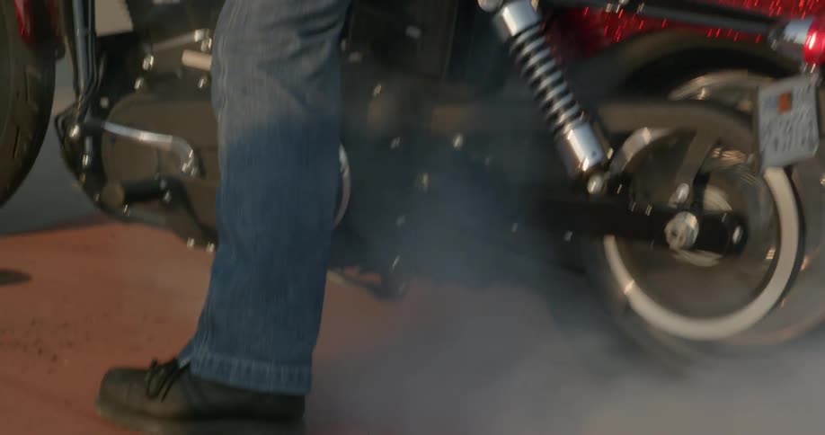 A man on a motorcycle is spinning the tires and making smoke