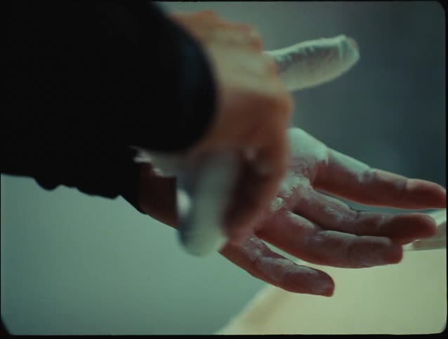 A woman rubs chalk all over her hands