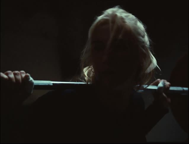 Woman works hard lifting weights indoors
