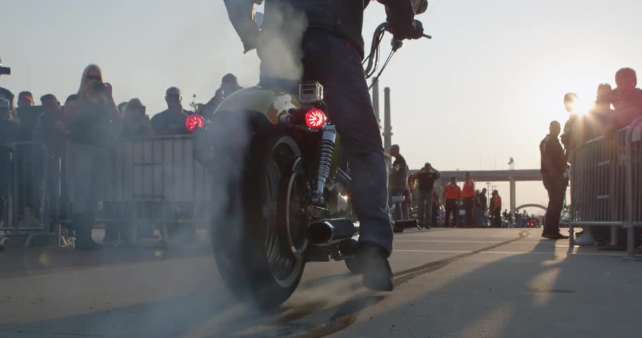 A motorcycle emits smoke as the driver comes to a stop