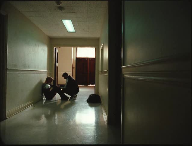 A man crouches by a woman sitting in the hallway
