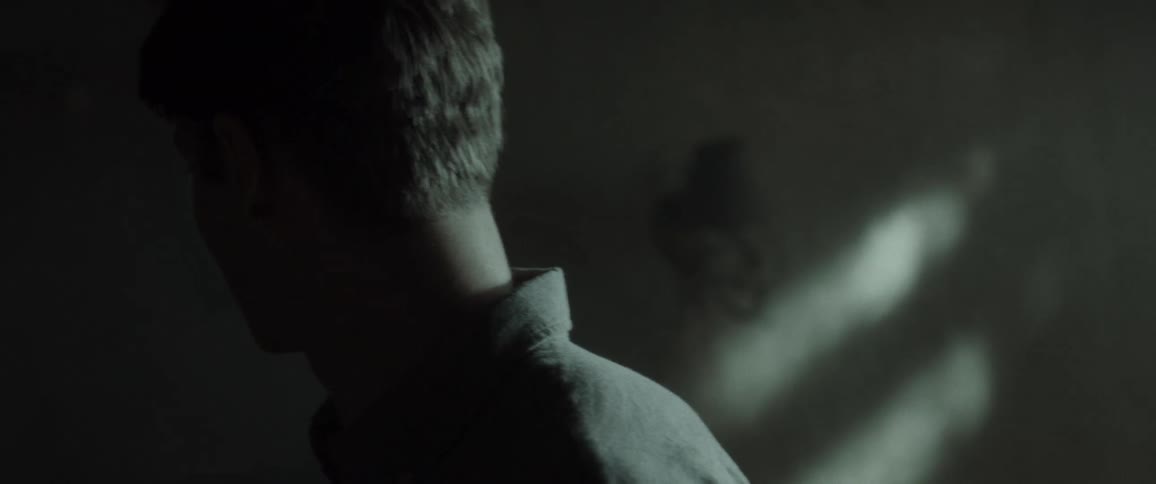 A man looks around nervously in the dark room
