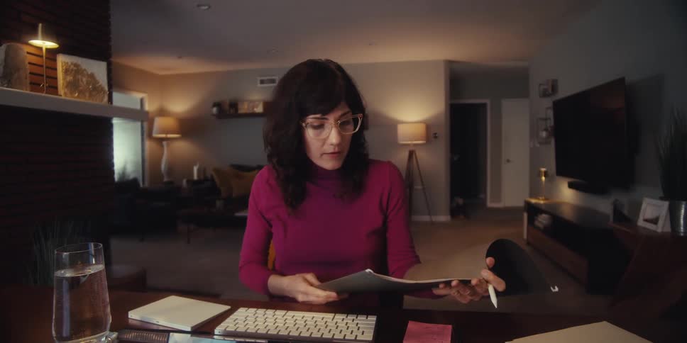 Woman in front of computer analyzing a folder of documents
