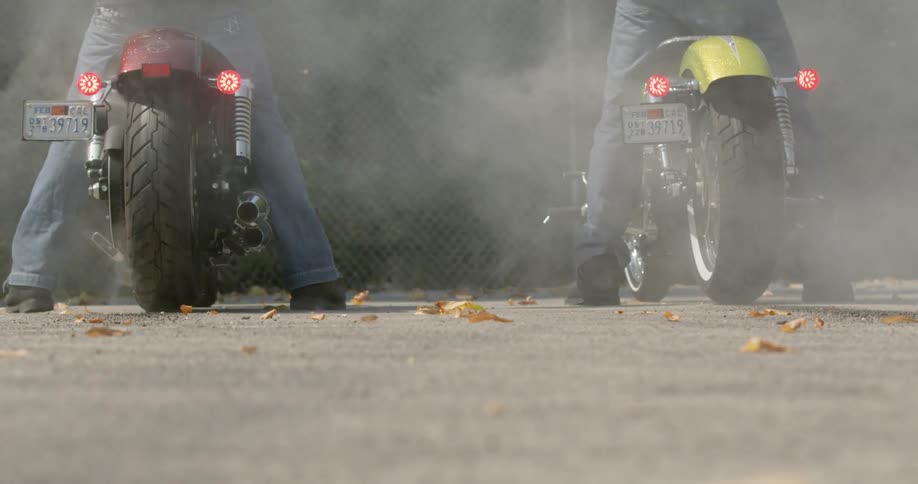 Two people revving motorcycles