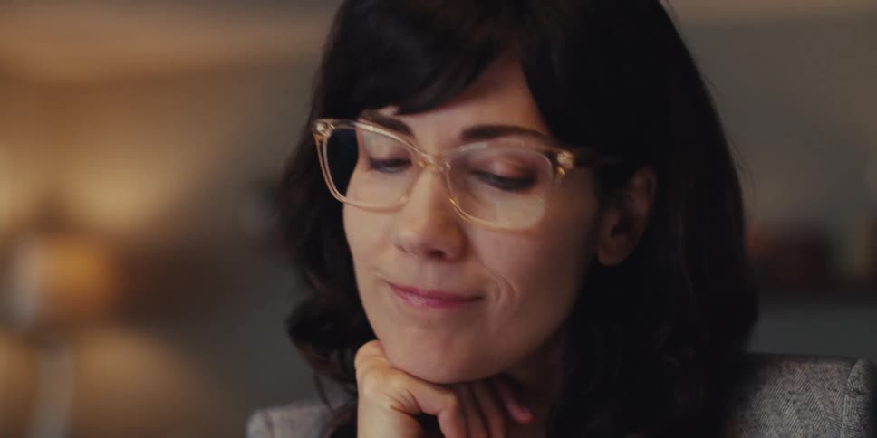 A woman in her home office thinking for a moment then smiling and typing on her computer